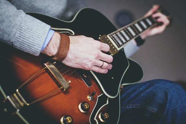 Blues Gitarre lernen – Nahaufnahme eines Mannes, der auf einer halbakustischen Gitarre spielt