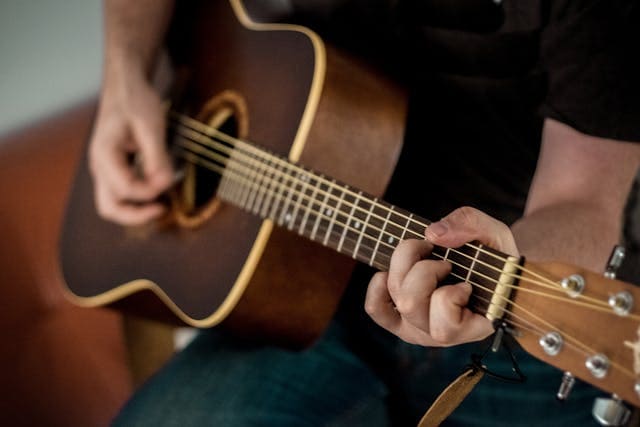 Mann spielt Akustikgitarre mit Akkorden – ideal für Einsteiger, die Gitarre lernen ohne Noten möchten.